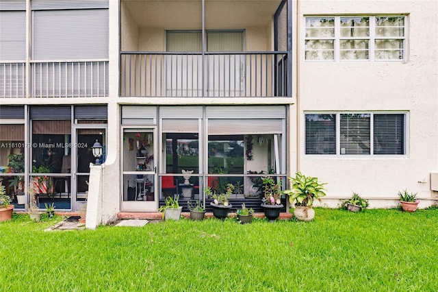 back of house featuring a balcony and a yard