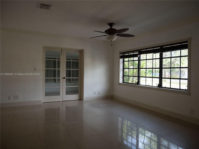 tiled spare room featuring ceiling fan, crown molding, and french doors