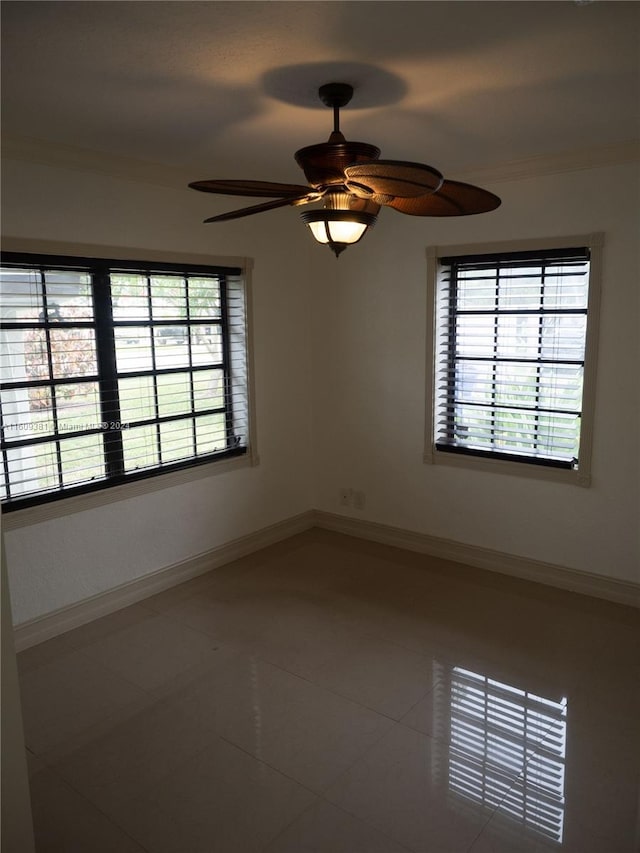 tiled empty room featuring ceiling fan and ornamental molding