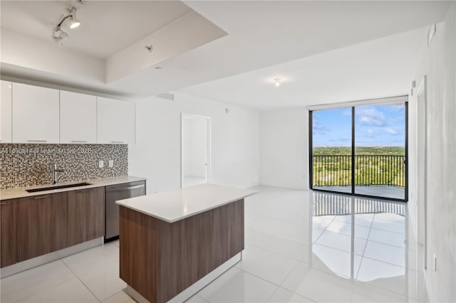 kitchen with a center island, stainless steel dishwasher, decorative backsplash, sink, and white cabinetry