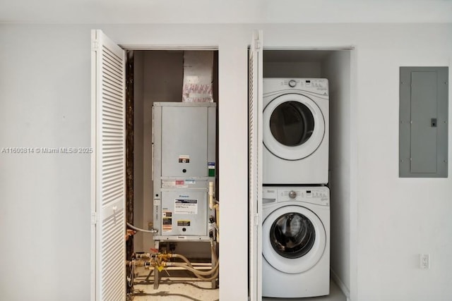 washroom featuring stacked washing maching and dryer, electric panel, and heating unit