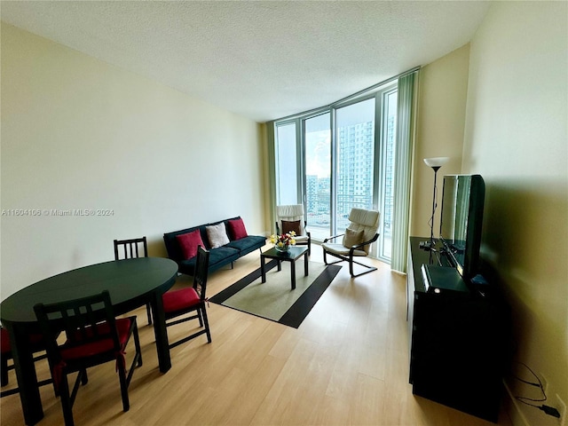 living room with floor to ceiling windows, light hardwood / wood-style floors, and a textured ceiling