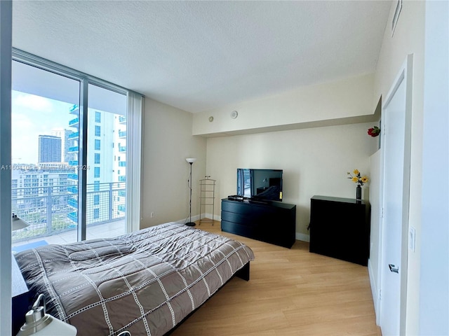 bedroom featuring a textured ceiling, floor to ceiling windows, and light hardwood / wood-style flooring