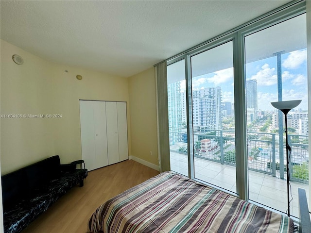 bedroom with a closet, expansive windows, a textured ceiling, light hardwood / wood-style flooring, and access to outside