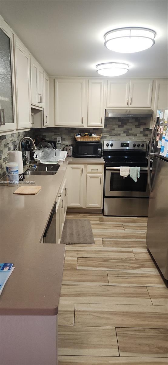 kitchen with white cabinets, decorative backsplash, sink, and appliances with stainless steel finishes