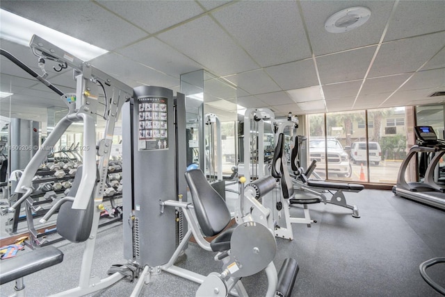 workout area with a drop ceiling and a wall of windows