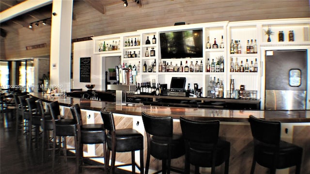 bar with wooden walls, refrigerator, and track lighting