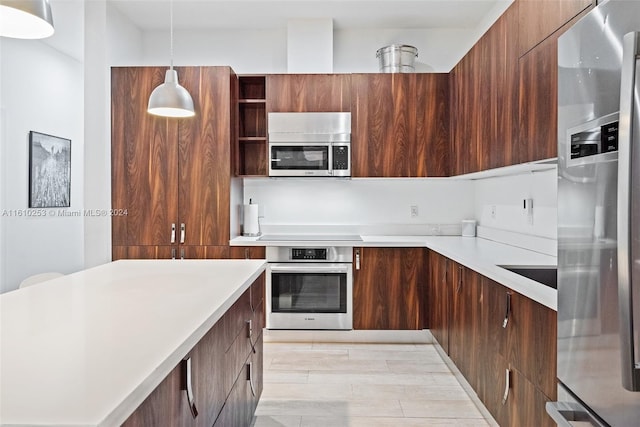 kitchen with appliances with stainless steel finishes, light hardwood / wood-style floors, and hanging light fixtures