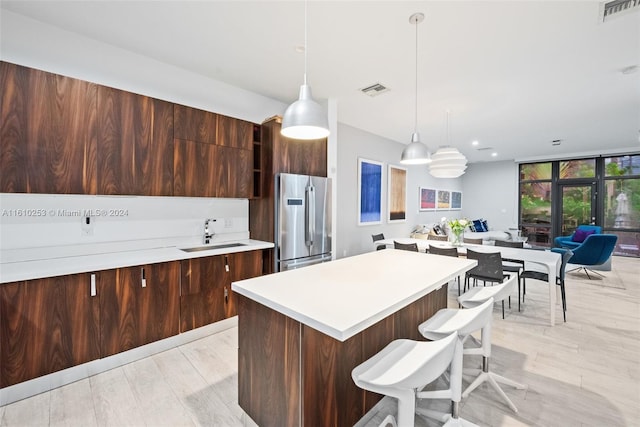 kitchen featuring stainless steel refrigerator, sink, french doors, light hardwood / wood-style flooring, and pendant lighting