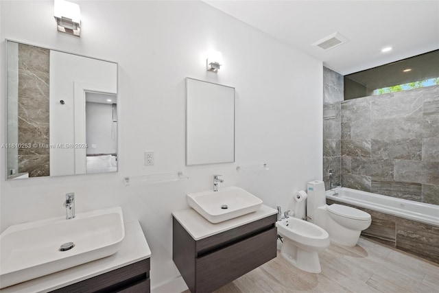 full bathroom with vanity, toilet, a bidet, and tiled shower / bath combo