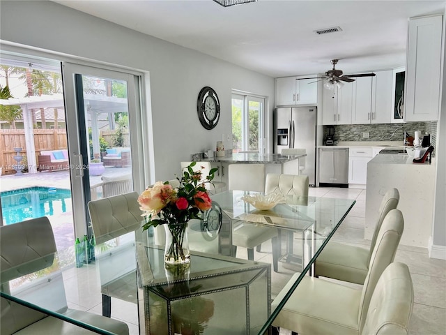 tiled dining space featuring ceiling fan and a healthy amount of sunlight