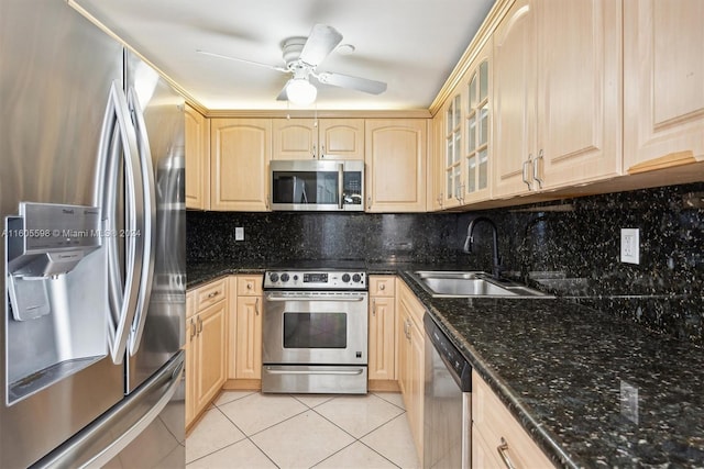 kitchen with decorative backsplash, dark stone counters, stainless steel appliances, sink, and light tile patterned floors