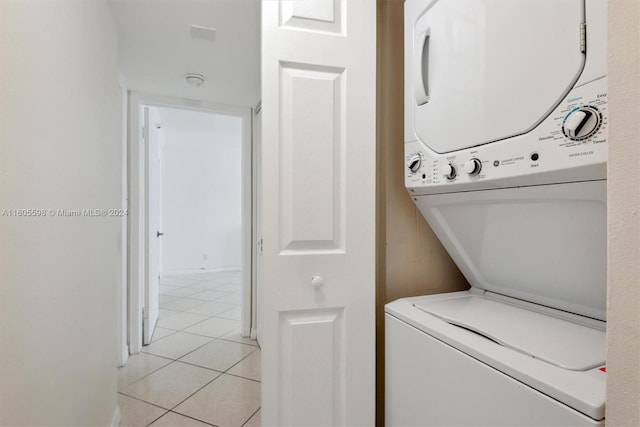 clothes washing area with stacked washer and dryer and light tile patterned floors