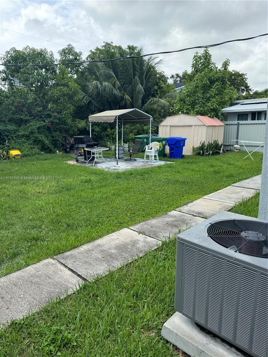 view of yard with a storage shed, cooling unit, and a patio