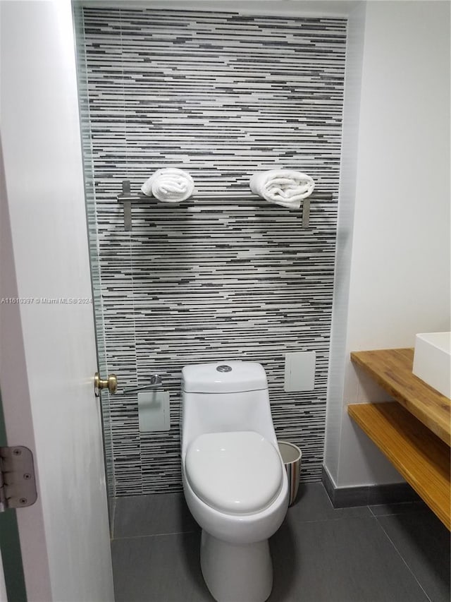 bathroom featuring tile flooring, toilet, and tile walls