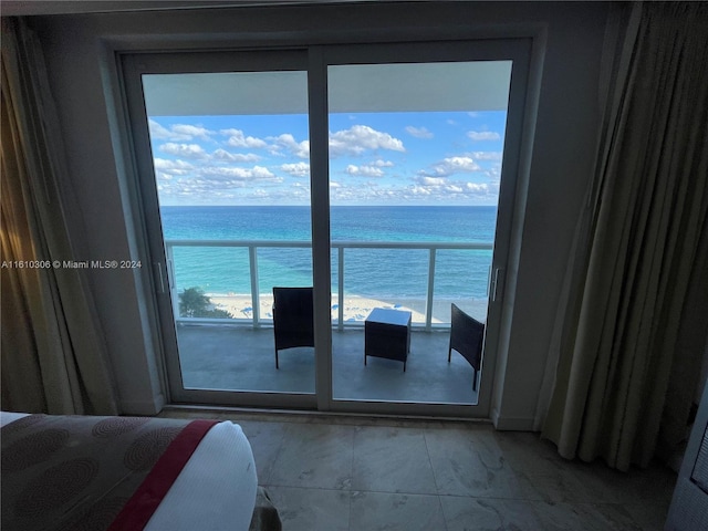 unfurnished bedroom featuring a beach view, a water view, and multiple windows