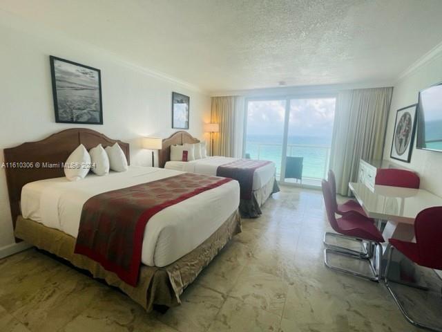 bedroom with crown molding, a water view, a textured ceiling, and access to outside