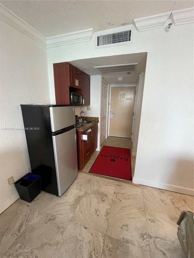 kitchen with sink, stainless steel fridge, ornamental molding, and a textured ceiling