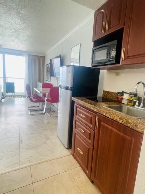 kitchen featuring stainless steel refrigerator, sink, crown molding, a textured ceiling, and light tile patterned flooring