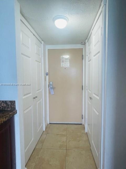 corridor featuring light tile patterned flooring and a textured ceiling