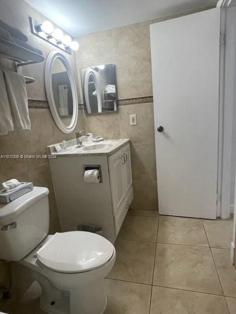 bathroom with tile patterned flooring, vanity, toilet, and tile walls