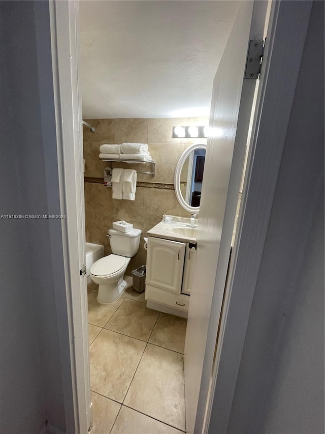 bathroom with toilet, vanity, tile patterned floors, and tile walls