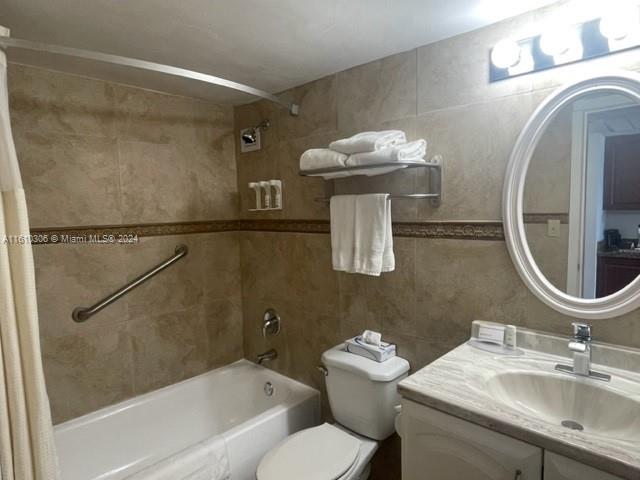 full bathroom with shower / tub combo with curtain, vanity, tile walls, and toilet