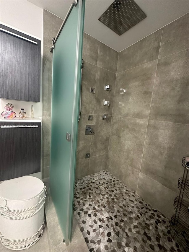 bathroom featuring tile patterned flooring, toilet, and a tile shower