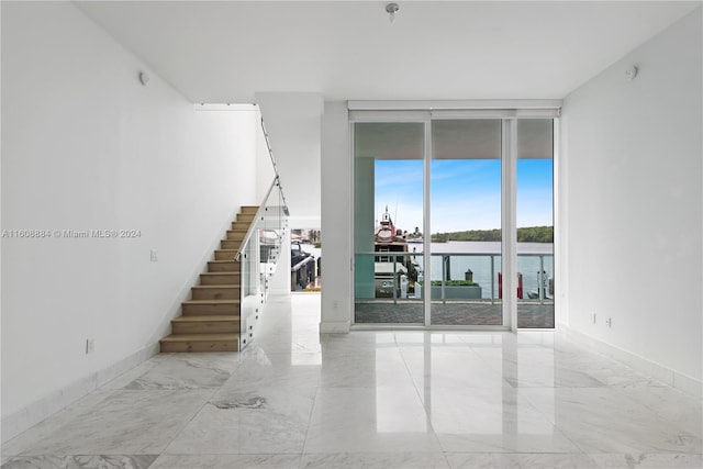 spare room with expansive windows and a water view