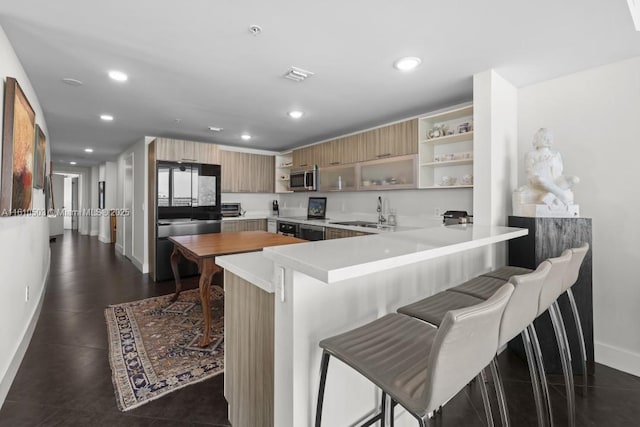 kitchen featuring a kitchen breakfast bar, kitchen peninsula, sink, and appliances with stainless steel finishes