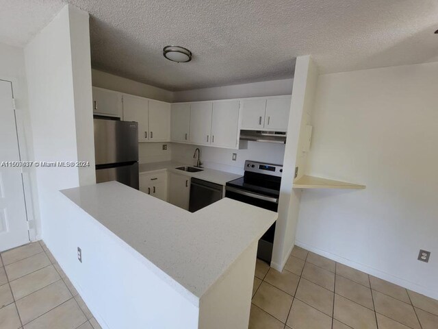 kitchen with kitchen peninsula, a textured ceiling, light tile floors, sink, and appliances with stainless steel finishes