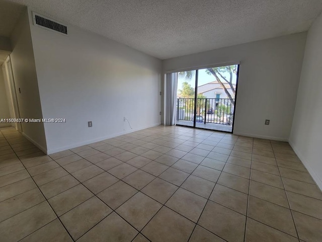 tiled spare room with a textured ceiling