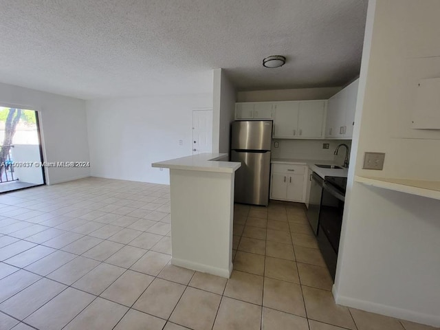 kitchen with kitchen peninsula, light tile floors, sink, white cabinets, and stainless steel refrigerator