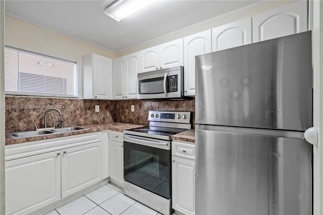 kitchen featuring decorative backsplash, appliances with stainless steel finishes, sink, light tile patterned floors, and white cabinets