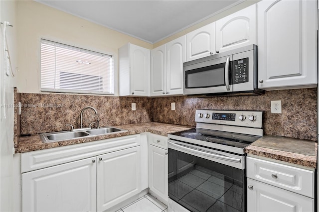 kitchen featuring decorative backsplash, stainless steel appliances, sink, light tile patterned floors, and white cabinetry