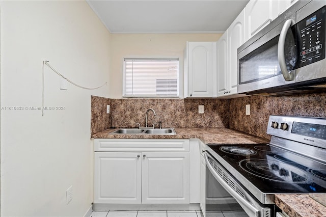 kitchen with sink, light tile patterned flooring, decorative backsplash, white cabinets, and appliances with stainless steel finishes