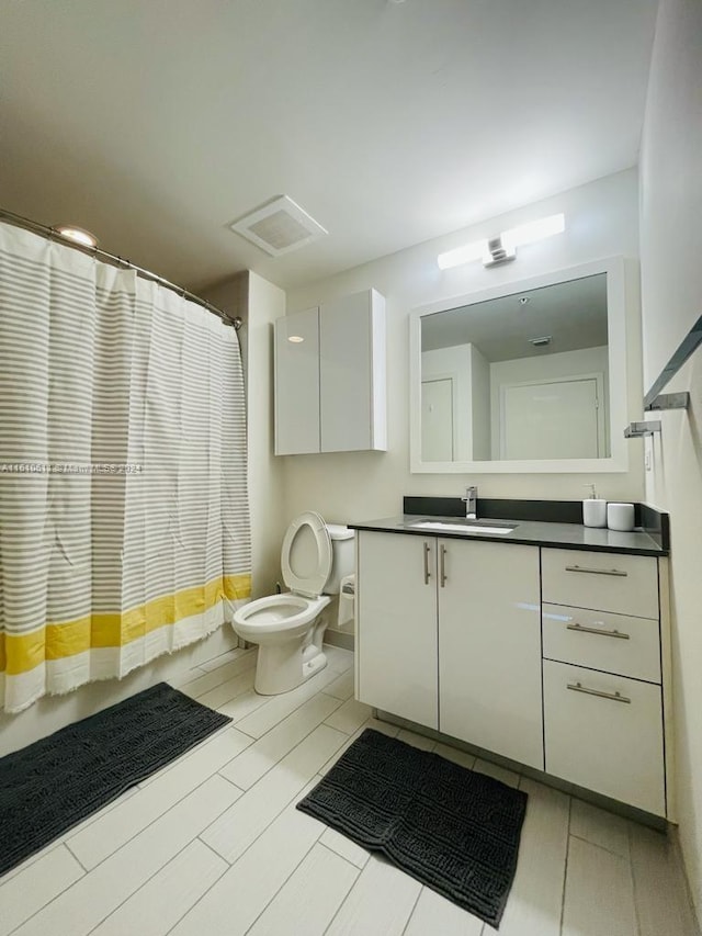 bathroom with tile flooring, toilet, and vanity