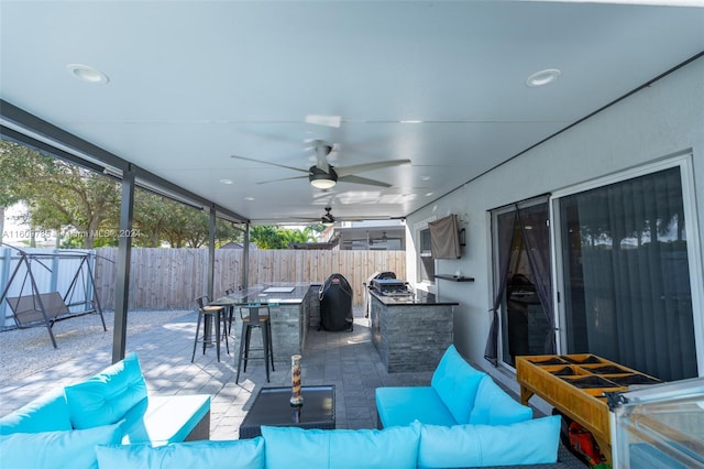 view of patio / terrace with a grill, an outdoor living space, an outdoor kitchen, ceiling fan, and an outdoor bar