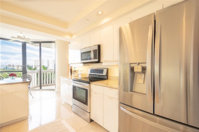 kitchen with appliances with stainless steel finishes, white cabinetry, light stone counters, and light tile patterned floors