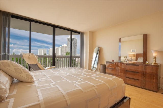 bedroom featuring floor to ceiling windows, light wood-type flooring, and access to exterior