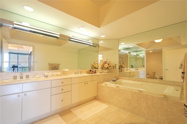 bathroom with vanity, toilet, tiled tub, and tile patterned flooring