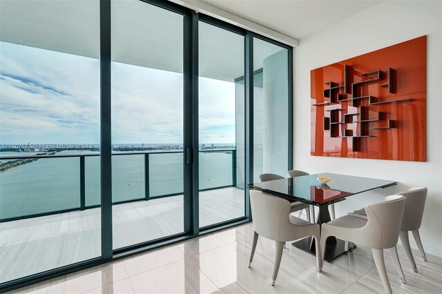 tiled dining space featuring floor to ceiling windows and a water view