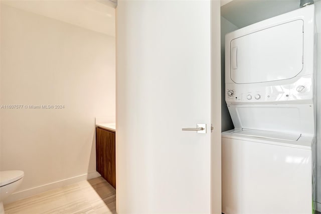 washroom featuring light hardwood / wood-style floors and stacked washing maching and dryer