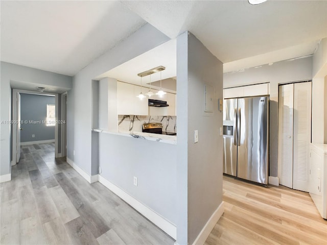 kitchen featuring white cabinets, pendant lighting, stainless steel appliances, and light hardwood / wood-style floors