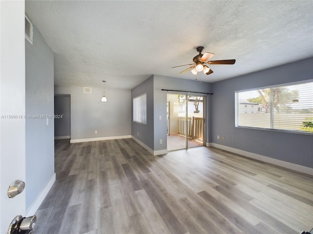 empty room with ceiling fan, a textured ceiling, and hardwood / wood-style flooring