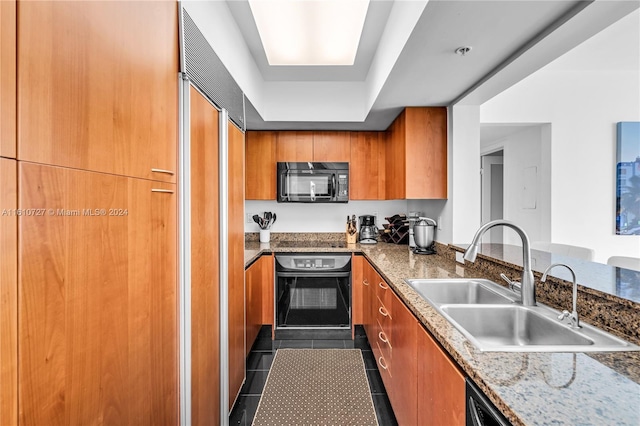 kitchen featuring light stone countertops, sink, dark tile patterned flooring, and black appliances