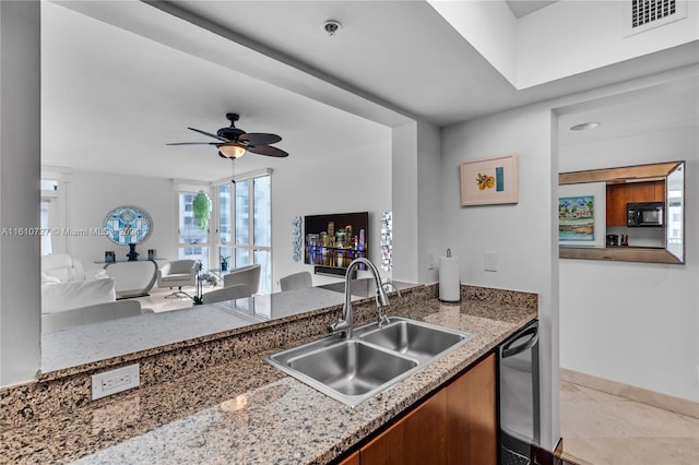 kitchen featuring ceiling fan, dishwasher, light stone countertops, and sink