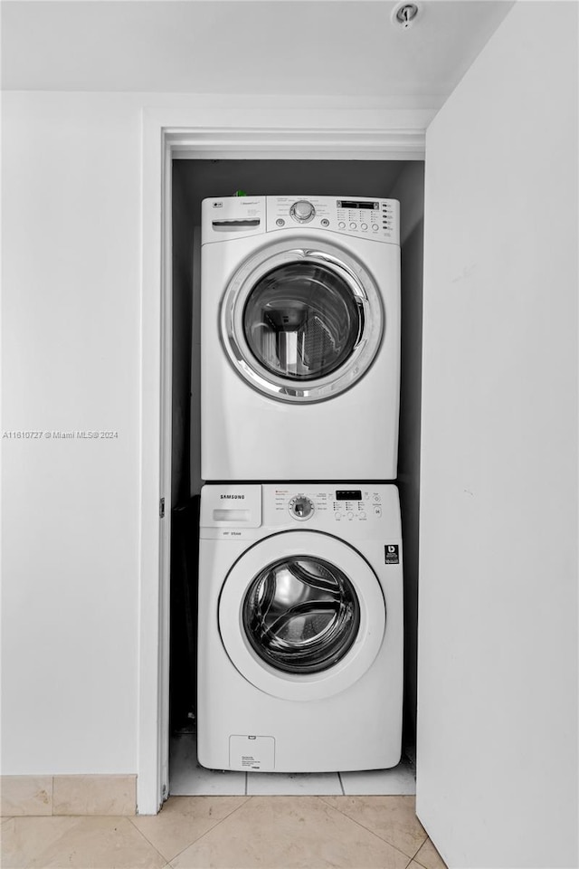 laundry area featuring light tile patterned flooring and stacked washer / dryer