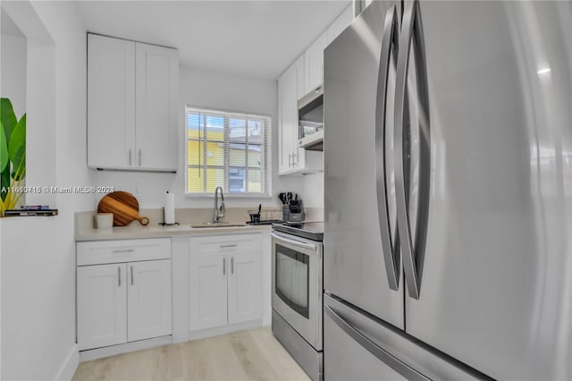 kitchen with light hardwood / wood-style floors, sink, white cabinetry, and stainless steel appliances