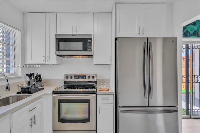 kitchen with stainless steel appliances, white cabinets, and sink